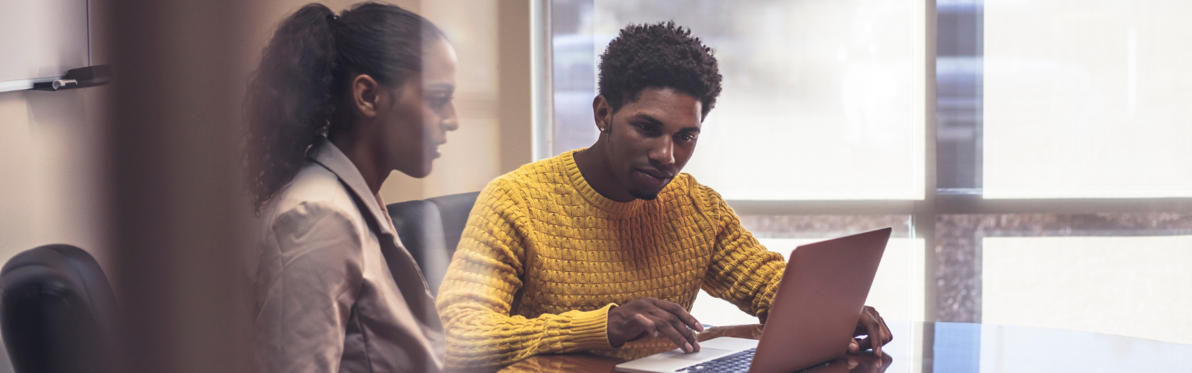 man and woman in office collaborating on laptop